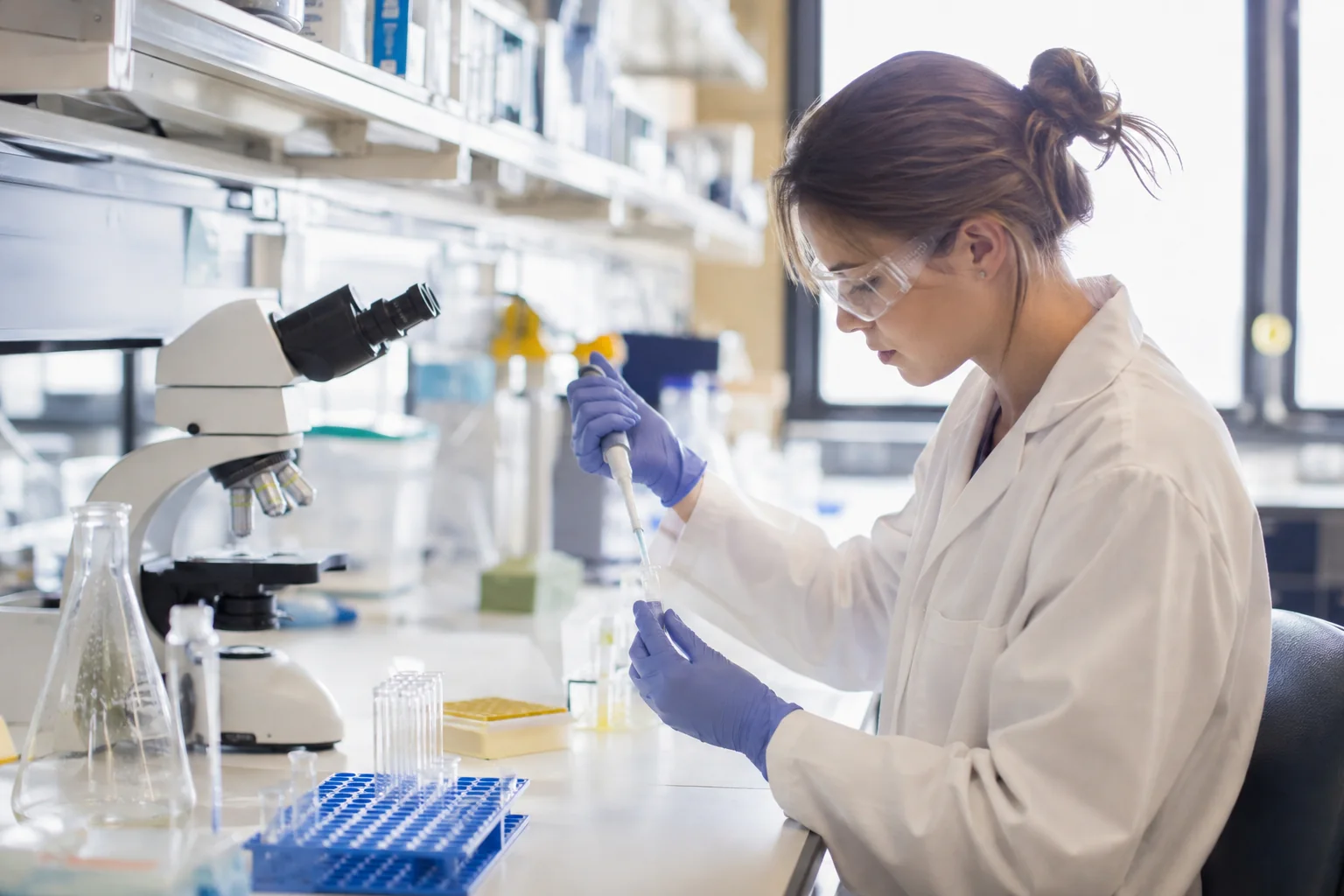 Scientist with a pipette and microscope at a laboratory bench